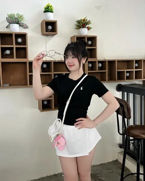 43 Avatar mặc đồ đen cô gái đứng trong quán với áo đen và váy trắng, tay đặt lên hông tạo dáng gọn, bố cục 2005 rõ người rõ nền nên nhìn khá ngầu và sáng