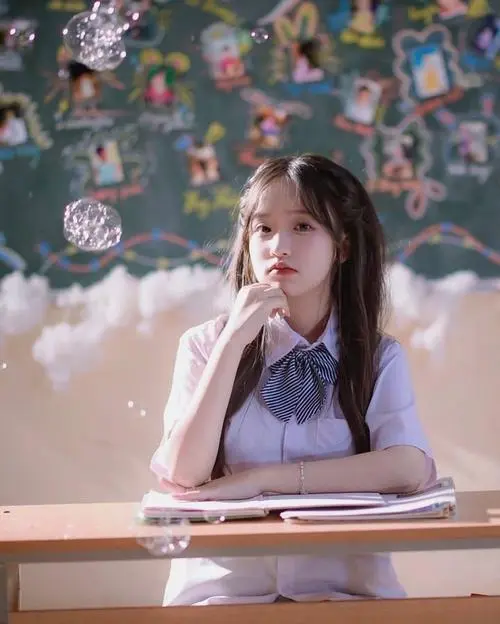 44 Cô bạn ngồi trước bàn học với váy tím, tay đặt gần cuốn sách và mắt nhìn lệch ra ngoài, ảnh 2k5 này mang chất học đường nhẹ nhàng, đúng kiểu những nàng thơ sinh năm 2005