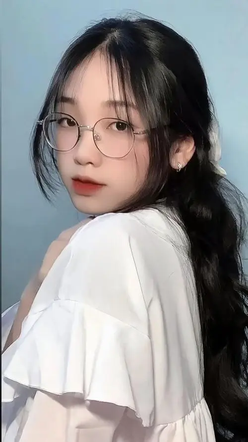 31 Avatar cận mặt cô bạn đeo kính mặc áo trắng chụp nghiêng trong nhà, một tay chạm gò má và tóc đen phủ vai, ánh sáng nhẹ làm gương mặt 2005 thêm đẹp và hiền
