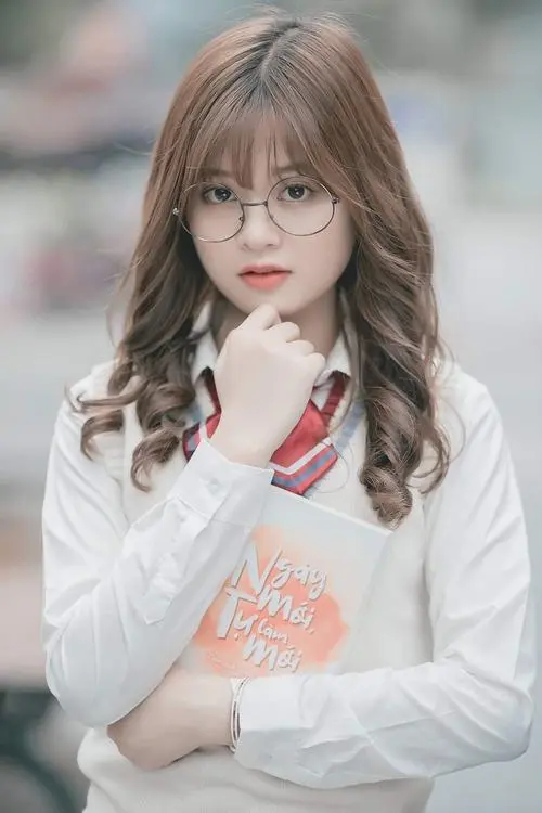 50 Bạn nữ tóc nâu sáng mặc áo trắng họa tiết cam, khoanh tay trước ngực và nhìn thẳng máy, nền mờ lạnh giúp chân dung 2k5 nổi mặt, hợp làm hình đại diện mỗi ngày