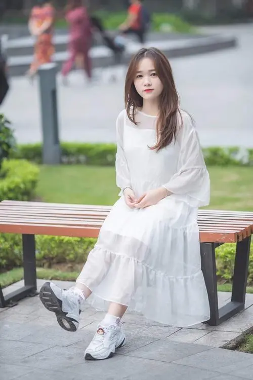 34 Bạn nữ mặc váy trắng ngồi trên ghế công viên, chân khép gọn và tay đặt bên cạnh, hậu cảnh cây xanh giúp ảnh 2005 trông mát mắt, hợp kiểu hình đại diện giản dị