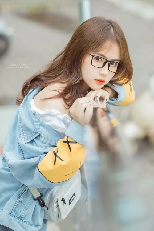 36 Cô bạn tóc sáng màu mặc áo xanh nhạt cầm quả cam gần miệng, nhìn lệch sang bên và ngồi giữa nền bokeh mềm, ảnh k5 lên màu ngọt nên khá dễ thương