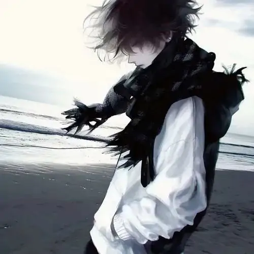 58 Cậu nam tóc nâu đứng cạnh giá sách cũ, một tay giữ gáy sách, hàng mi cụp xuống và màu phim xám làm khung hình có chút hoài niệm đầy tự nhiên