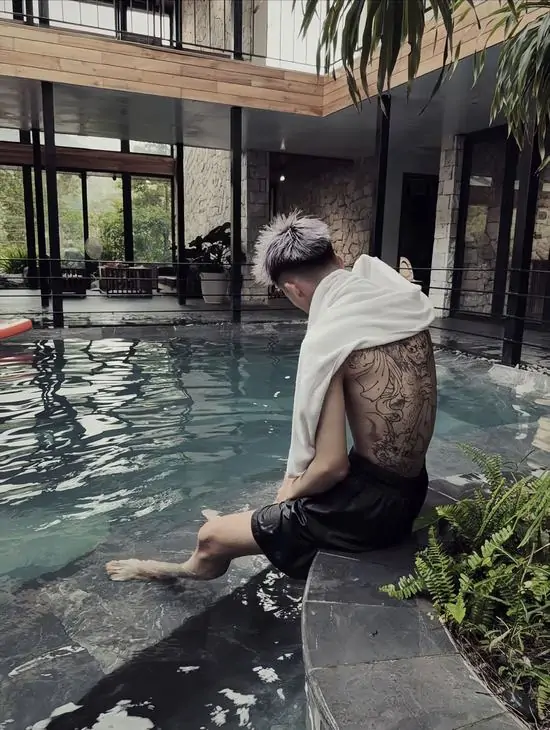 16 Chàng trai ngồi nghỉ bên thành hồ bơi, làn nước xanh trong làm nổi bật những hình vẽ phong trần trải dài khắp bờ vai rộng và vạm vỡ.