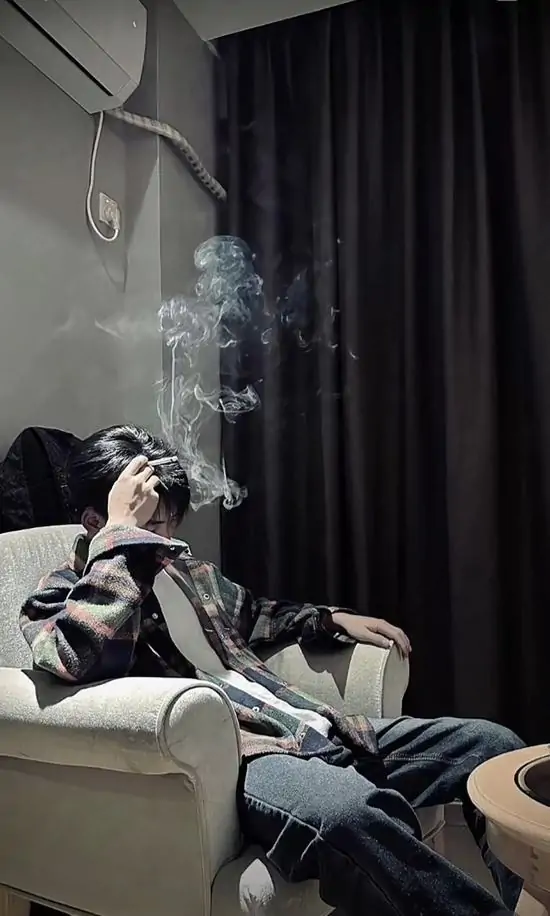 14 Chàng trai nằm dài trên ghế sofa trong phòng, cầm điếu thuốc hút, khói bay lên trần nhà, vẻ run rẩy.
