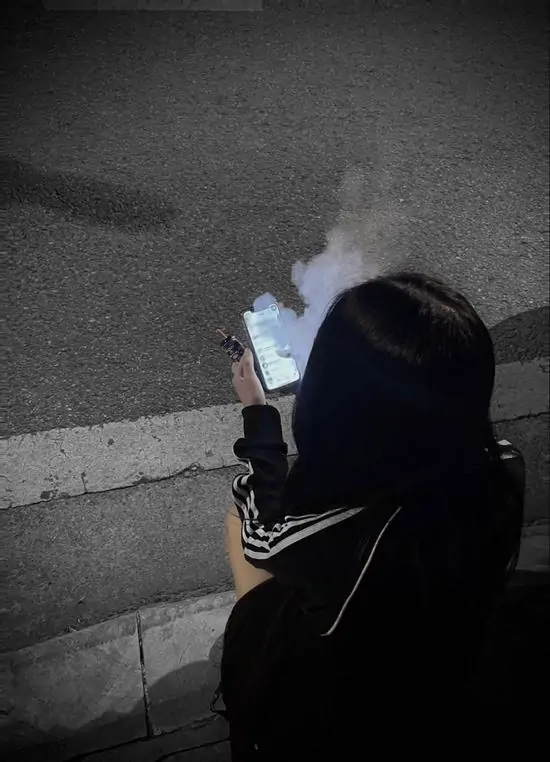 16 Người mặc hoodie đứng hút thuốc trên phố đêm mưa, khói bay lẫn với sương, siết chặt.