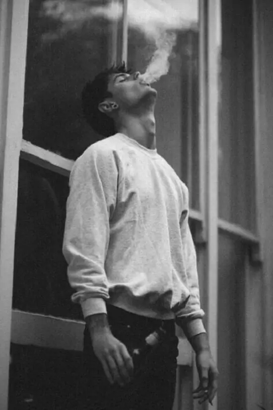 29 Khoảnh khắc chàng trai mặc áo trắng đứng bên cửa sổ, cầm điếu thuốc nhìn ra ngoài, hoang vắng.