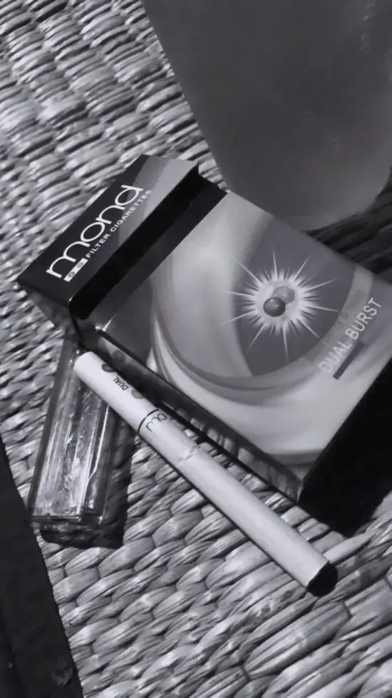 7 Hình nền bàn tay cầm điếu thuốc bên cạnh bật lửa và gói thuốc lá trên bàn gỗ, điện thoại nằm cạnh, toát vẻ mệt mỏi.