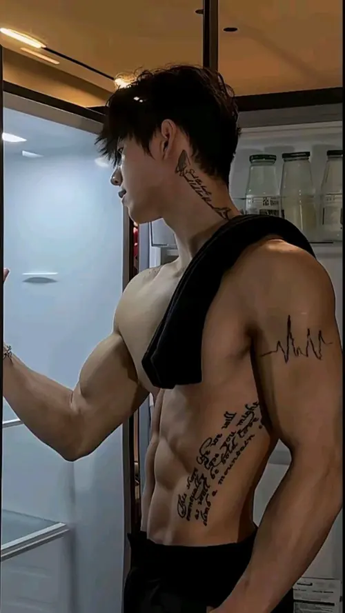 24 Trong hành lang sáng ấm, chàng trai mặc áo sát nách đen, hình xăm bên sườn lộ rõ
