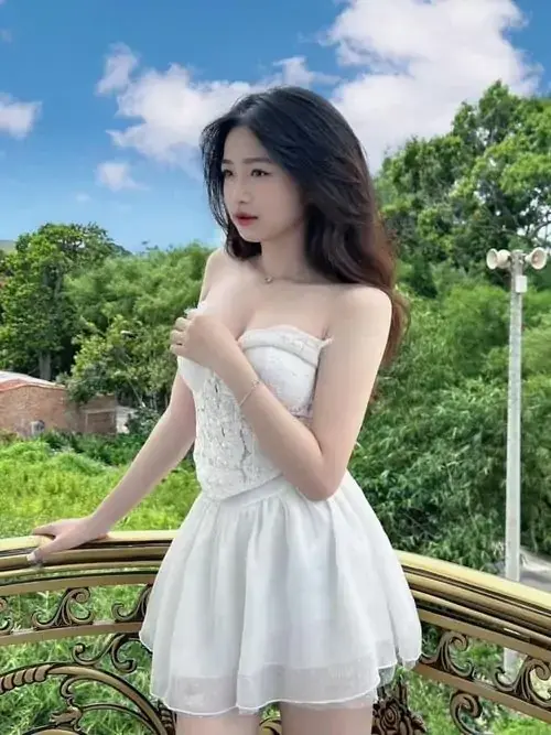 7 Cô gái mặc váy trắng cúp ngực đứng bên lan can gỗ, phía sau là trời xanh và vườn cây