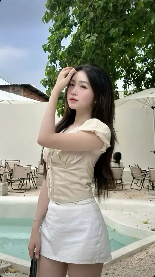 9 Nàng tóc dài mặc váy trắng ôm nhẹ, đứng cạnh hồ bơi và đưa tay che nắng