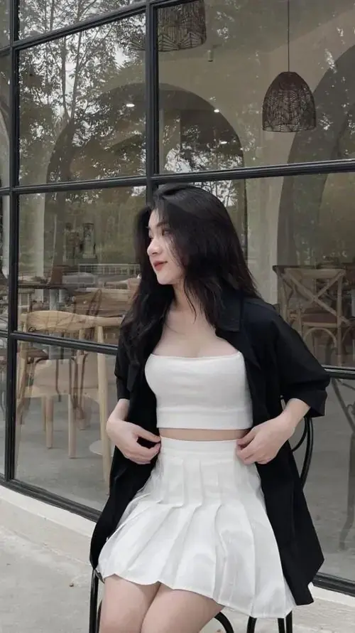 11 Cô nàng mặc set trắng đứng cạnh khung kính cao, tóc đen dài và dáng pose nghiêng nhẹ