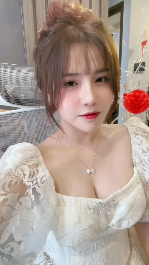 9 Trong khung hình phòng ngủ, cô gái tóc buộc cao mặc váy ren trắng, vú tròn đầy lộ nhẹ
