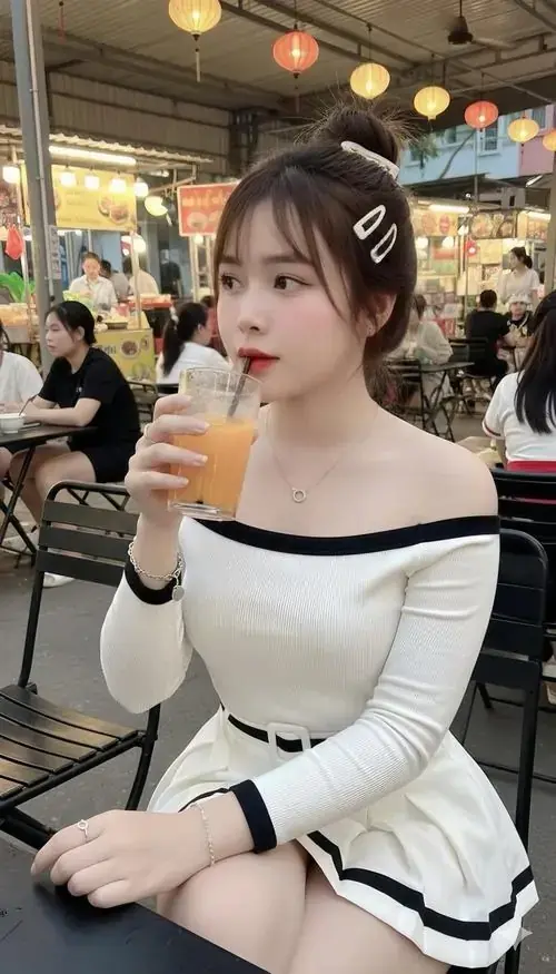 4 Giữa quán đông người, cô nàng mặc áo trễ vai trắng đen cầm ly nước, mắt nhìn xa