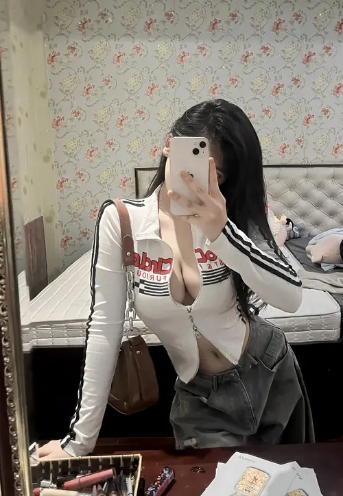 4 Trước gương phòng ngủ, cô nàng cầm điện thoại che mặt, áo trắng ôm dáng và váy ngắn tối màu