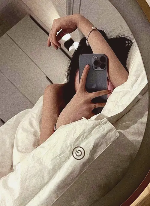 2 Trong góc chụp gương trên giường, cô nàng mặc áo choàng trắng che mặt bằng điện thoại và đưa tay lên tóc