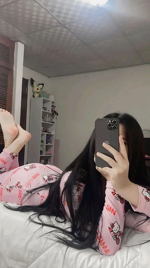 8 Trong căn phòng ngủ sáng, cô nàng ngồi trên giường chụp gương, tóc đen phủ vai và áo tối màu