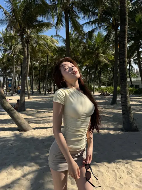 3 Cô gái tóc đen đứng giữa bãi biển hàng dừa mặc áo ôm dáng và cười nhẹ