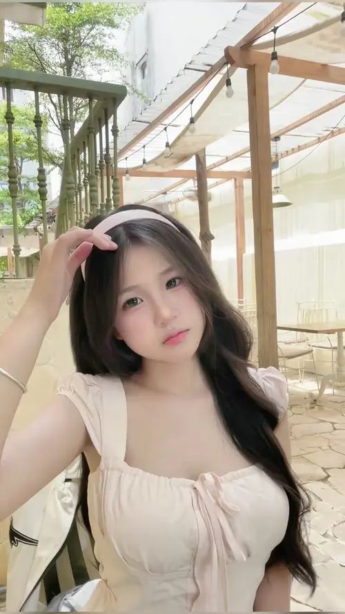 15 Người đẹp Việt mặc áo trắng bèo ngồi dưới mái hiên gỗ, một tay khẽ giữ tóc