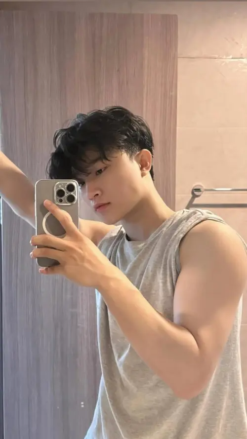 14 Trước gương phòng sáng, cậu bạn đeo kính mặc áo polo xanh đậm, khoanh tay nhìn thẳng camera