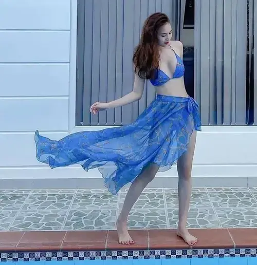 9 Người mẫu nữ mặc bikini xanh phối váy voan, bước nghiêng bên hồ bơi với mái tóc dài