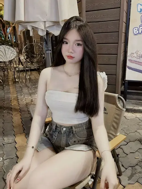 3 Áo vàng hai dây ôm phần vú, cánh tay giơ cao trên nền tường xám.