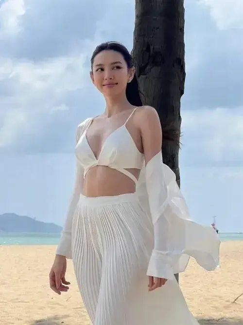 5 Miss Grand 2021 mặc bikini trắng cùng váy lưới mỏng, đứng cạnh thân cây và nhìn thẳng bình thản