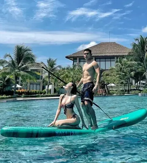 22 Trên ván chèo giữa hồ xanh, cô gái mặc đồ bơi đen ngồi tạo dáng trước khu villa