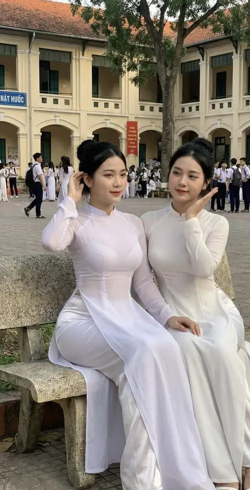 3 Hai học sinh nữ ngồi trên ghế đá, áo dài trắng gọn gàng giữa sân trường giờ ra chơi.