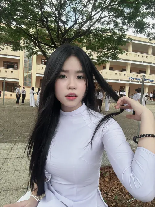 4 Gương mặt nhìn thẳng vào máy ảnh, cô bạn tóc dài mặc áo dài trắng trong khung sân trường.