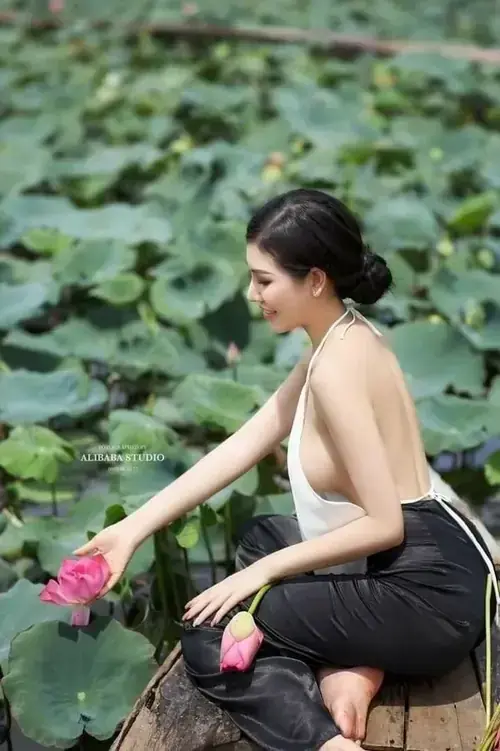 12 Bên hồ sen xanh, người mẫu mặc váy đen hở lưng cúi xuống chạm vào cánh sen
