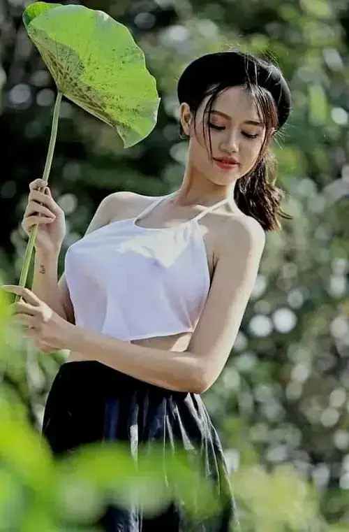 14 Chiếc ô giấy nghiêng trên vai, người mẫu mặc áo trắng đứng giữa lùm cây xanh