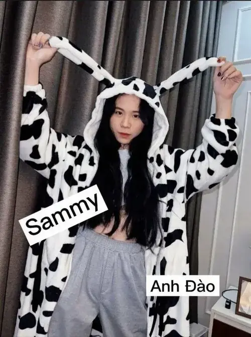 9 Bộ đồ bò sữa nổi bật, cô nàng gamer giơ hai tay vui vẻ, tóc dài và bảng tên Sammy