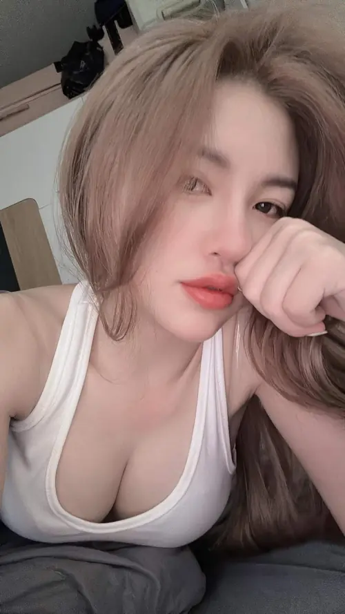 20 Tóc nâu uốn nhẹ, áo hoa cổ thấp lộ ngực và vòng cổ nhỏ ở khung nửa người.