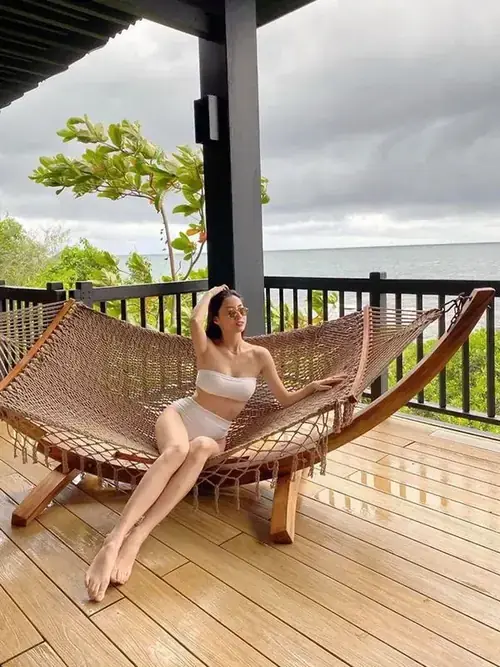 10 Trên ban công khu nghỉ dưỡng, Thùy Tiên nằm võng với áo tắm trắng, dáng ngồi thả lỏng
