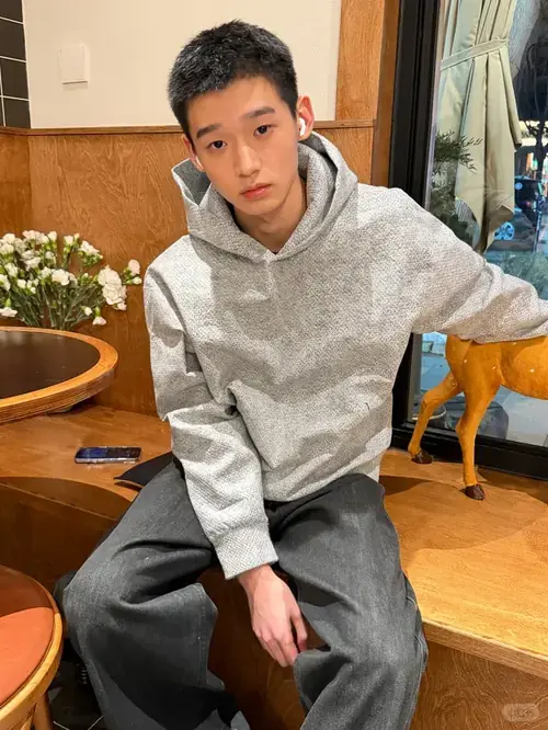 3 Nam sinh mặc hoodie xám ngồi trong quán, gương mặt gọn gàng và dáng ngồi khá thoải mái