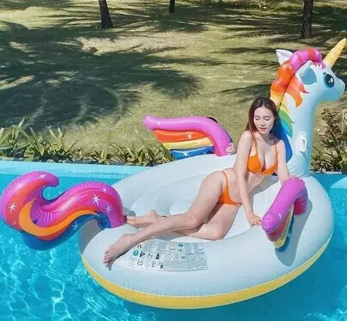 26 Trên phao kỳ lân nhiều màu ở hồ bơi, cô gái mặc áo trắng cười nhẹ dưới bóng cây