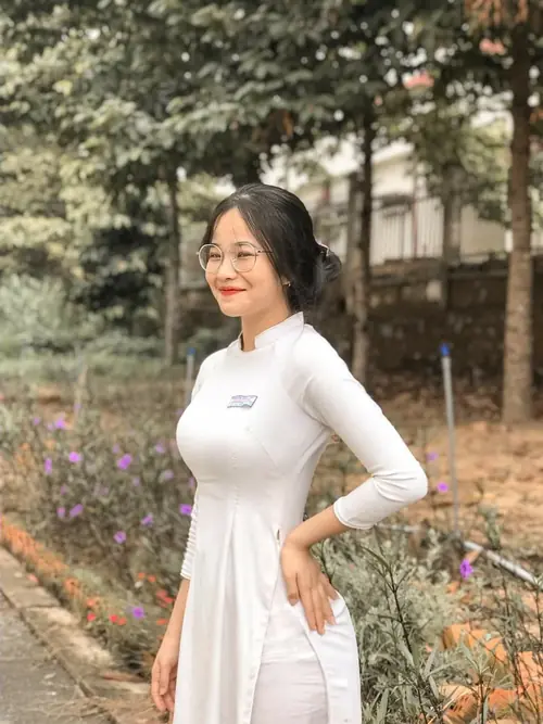 10 Bên lối cây trong sân trường, thiếu nữ áo trắng đứng nghiêng người, tay đặt ở eo.