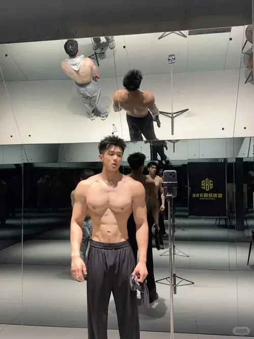 21 Dáng đứng chính diện trong phòng gym cho thấy chàng trai mặc quần đen, tóc dày và vai rộng