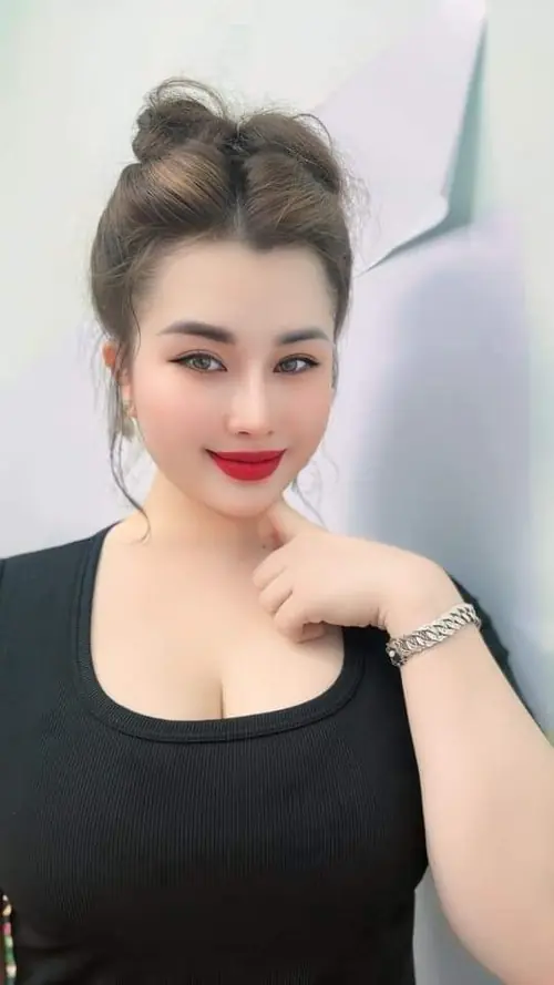 23 Cô nàng váy hồng ngồi trên ghế mây, tay đặt nhẹ và mỉm cười trong quán cà phê