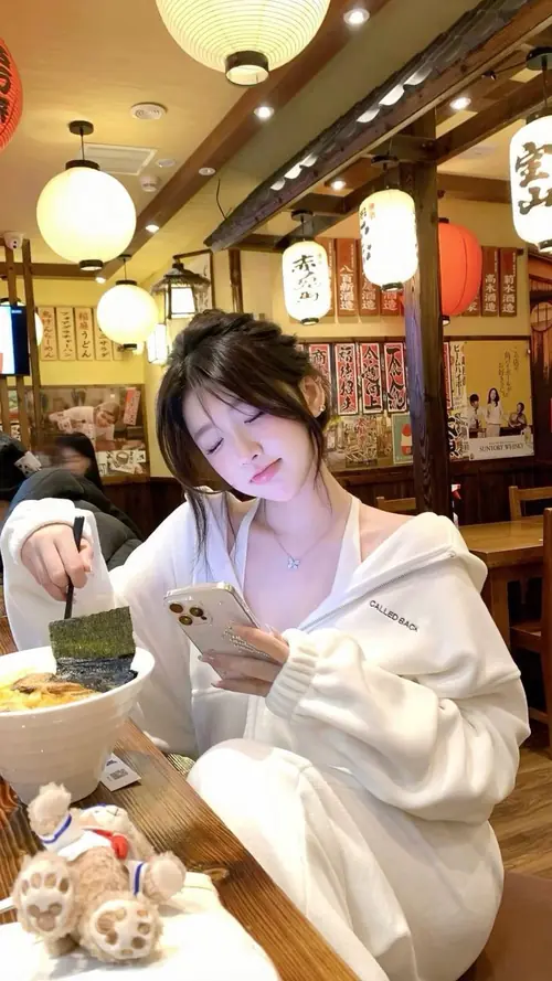 9 Bạn nữ ngồi trong quán ấm đèn vàng, mặc hoodie trắng và nhìn máy ảnh đầy tinh nghịch