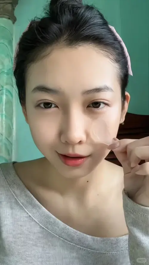 14 Trong khung hình cận mặt cô nàng buộc tóc mặc áo xám lệch vai đưa tay chạm má