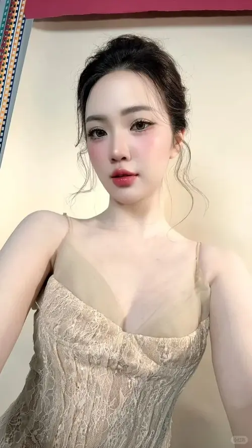 16 Ở góc chụp cận mặt, cô nàng búi tóc mặc áo ren be, môi đỏ và ánh nhìn thẳng