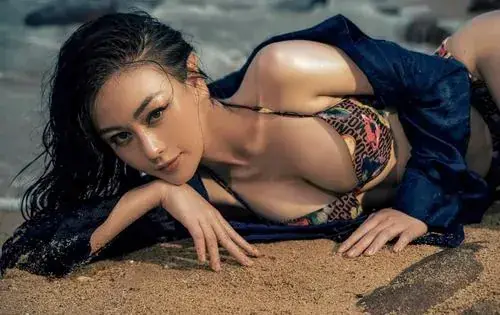 5 Người mẫu ảnh nằm trên cát ướt cạnh bờ biển, mặc bikini họa tiết và chống tay nhìn thẳng vào ống kính