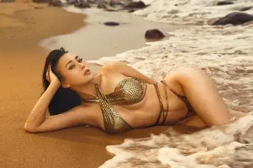 14 Trên bãi cát sáng, mỹ nhân phim Việt nằm nghiêng với bikini ánh vàng, mái tóc đen trải nhẹ trên vai